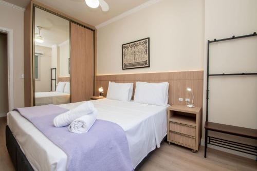 Un dormitorio con una gran cama blanca y un espejo. en Conforto em Apto no Jurerê Open Shopping P1529, en Florianópolis