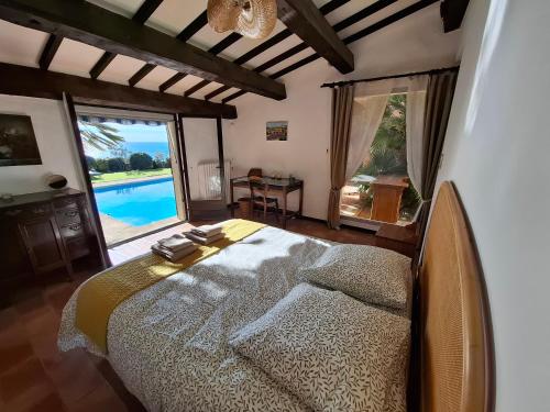 une chambre avec un lit avec vue sur une piscine dans l'établissement La Roche Bleue - Villa de charme avec vue exceptionnelle bord de mer piscine privée jardin et terrasse, à Carry-le-Rouet