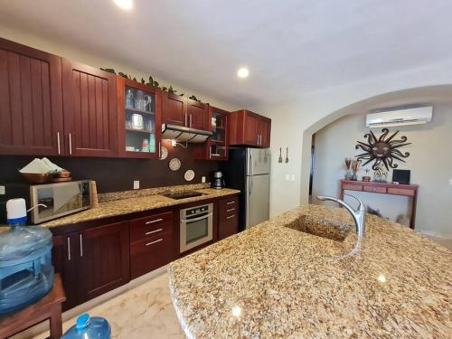 a kitchen with wooden cabinets and a granite counter top at Villa 301, Ground floor, Oceanfront! in Mahahual