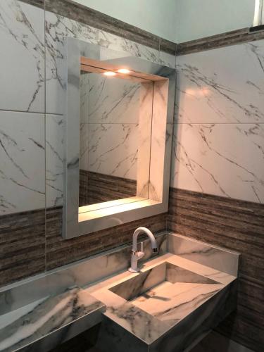 un bagno con lavandino e specchio di Pousada Samreny a Maracanã