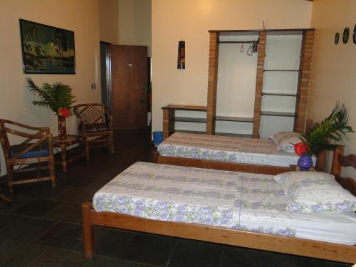 a bedroom with two beds and a table and a chair at Hotel Pousada Arco Iris in Barra de Santo Antônio