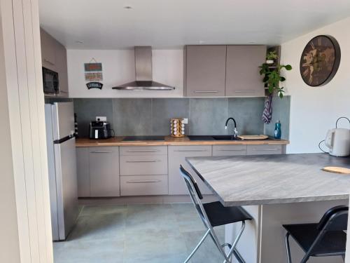 une cuisine avec des armoires blanches et une table avec des chaises dans l'établissement Maison de vigne pleine de charme, à Millau