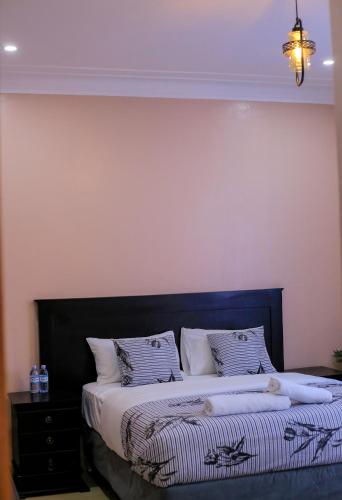 a bedroom with a bed with a black headboard at Dreamy Den Suites Kiwatule in Kampala