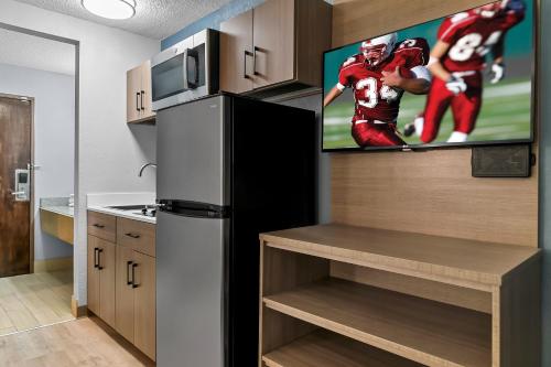 a kitchen with a black refrigerator and a tv at HomeTowne Studios by Red Roof Flint in Flint