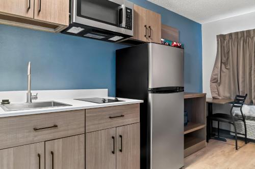 a kitchen with a refrigerator and a sink at HomeTowne Studios by Red Roof Flint in Flint