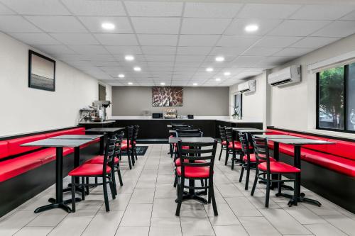 a restaurant with red chairs and tables in a room at HomeTowne Studios by Red Roof Flint in Flint