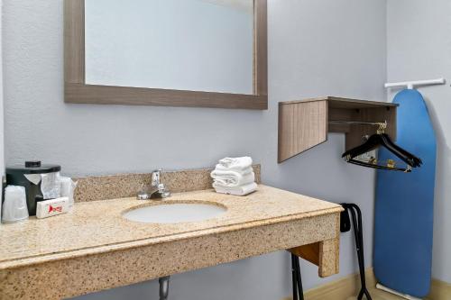 a bathroom with a sink and a mirror at HomeTowne Studios by Red Roof Flint in Flint