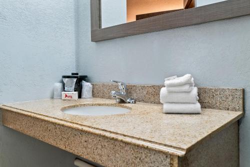 a bathroom counter with a sink and a mirror at HomeTowne Studios by Red Roof Flint in Flint