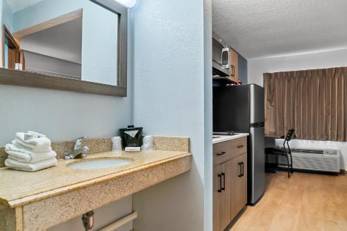 a kitchen with a sink and a refrigerator at HomeTowne Studios by Red Roof Flint in Flint