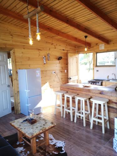 a kitchen with a refrigerator and a table in a cabin at Rukawe Quillon in Quillón