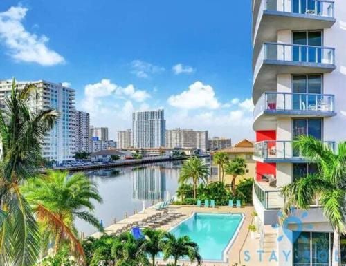 a building with a swimming pool next to a body of water at Modern New Studio Balcony & Pool in Hallandale Beach