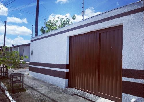 a brown garage door on a white building at Casa Jardim PINHEIROS in Maceió