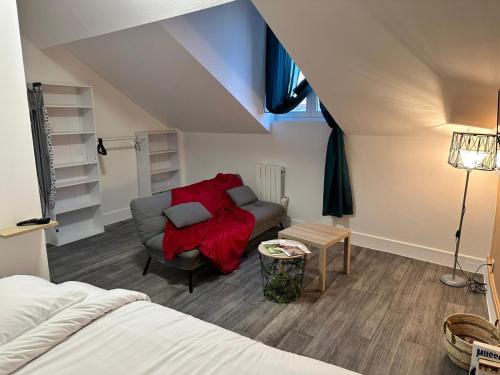 - une chambre avec un canapé et une couverture rouge dans l'établissement Le MONTLUSPOT, à Montluçon