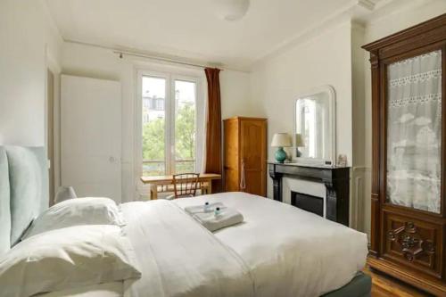une chambre avec un grand lit blanc et une fenêtre dans l'établissement Bel appartement parisien - Les Gobelins, à Paris