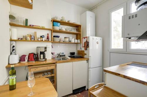 Il comprend une cuisine équipée d'un réfrigérateur blanc et d'une table en bois. dans l'établissement Bel appartement parisien - Les Gobelins, à Paris