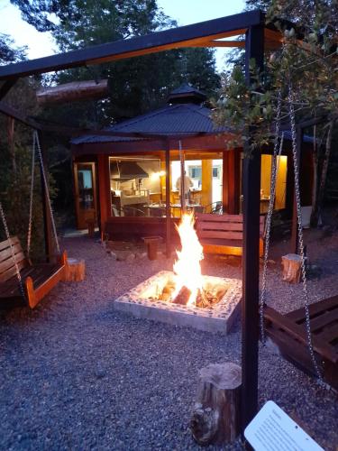 a fire pit in front of a log cabin at Cuyinco Domos in Riñinahue