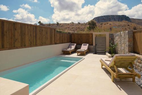 a swimming pool with two lounge chairs next to a fence at The Z Suites in Gournes
