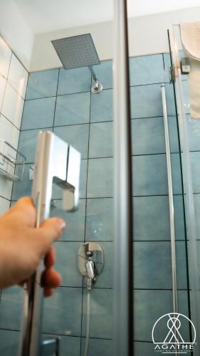 a person opening a shower door in a bathroom at Agathè Luxury Bed and Breakfast in Marina di Schiavonea