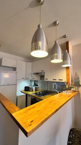 une cuisine avec un comptoir et trois lampes suspendues dans l'établissement Joli appartement T3 Coum a Case, à Vernet-les-Bains