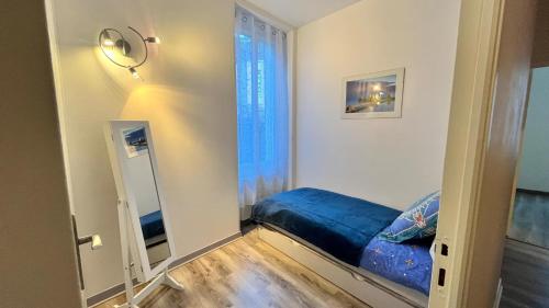 Cette chambre dispose d'un lit bleu et d'un miroir. dans l'établissement Joli appartement T3 Coum a Case, à Vernet-les-Bains