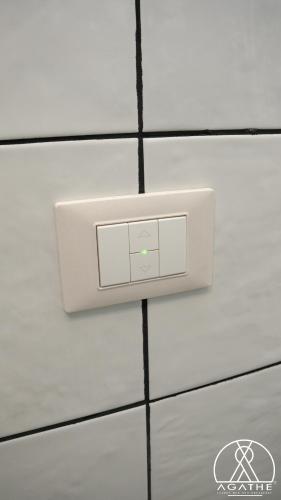 a white lightswitch on a white tiled wall at Agathè Luxury Bed and Breakfast in Marina di Schiavonea