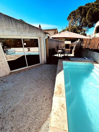 - une piscine à côté d'une maison avec un parasol dans l'établissement Mas provençal avec piscine - Coin de Paradis, à Puget-sur Argens