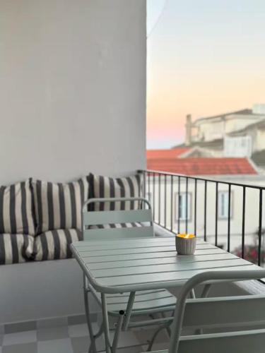 een tafel en stoel op een balkon met een bank bij RookieC Two Bedroom peaceful location old town AC in Cascais