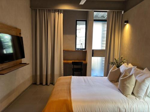 a hotel room with a bed and a television at Departamentos y Suites Índigo in Querétaro