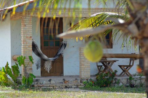 a white house with a wooden door and a table at Pousada Oceania in Taíba