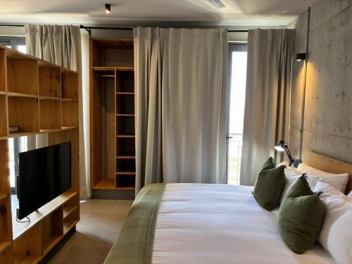 a bedroom with a large bed with a flat screen tv at Departamentos y Suites Índigo in Querétaro
