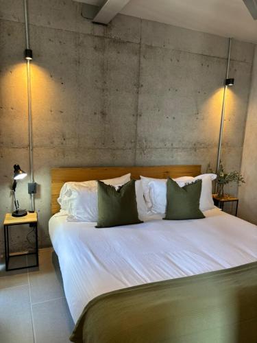 a large bed with white sheets and green pillows at Departamentos y Suites Índigo in Querétaro