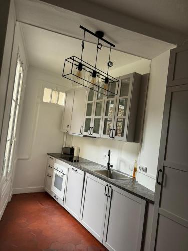 une cuisine avec des armoires blanches et un évier dans l'établissement Maison cosy Paris centre avec jardin, à Paris