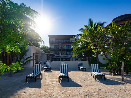 a group of chairs sitting in the sand near a building at Beachfront Hotel Boutique DK in Holbox Island