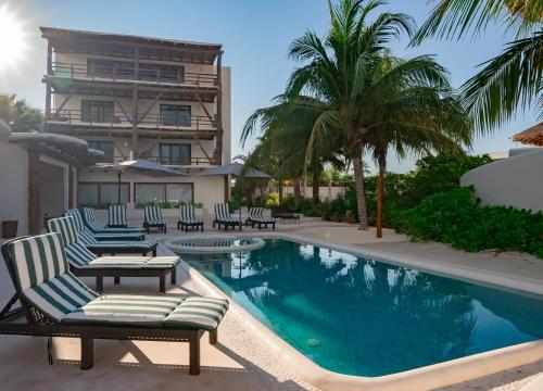 a swimming pool with lounge chairs and a building at Beachfront Hotel Boutique DK in Holbox Island