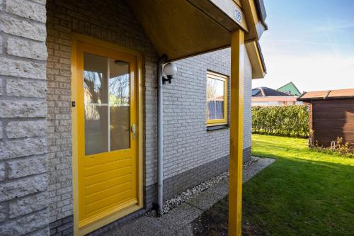 a yellow door on the side of a house at Tulip Beach in De Zandloper