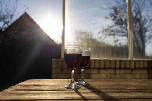 two glasses of red wine sitting on a wooden table at Tulip Beach in De Zandloper