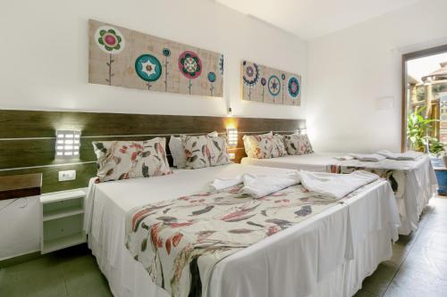 two beds in a room with white walls at VELINN Pousada Iguana Azul in Ilhabela