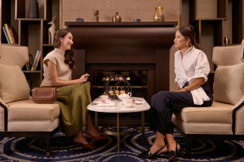 two women sitting in chairs in a living room at The St. Regis Astana in Astana