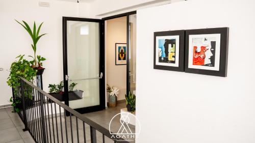 a hallway with an open door with pictures on the wall at Agathè Luxury Bed and Breakfast in Marina di Schiavonea