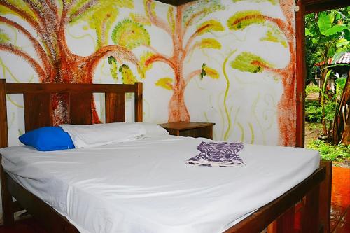 een bed in een slaapkamer met een muurschildering van een boom bij Hostal La Gloria in Mérida