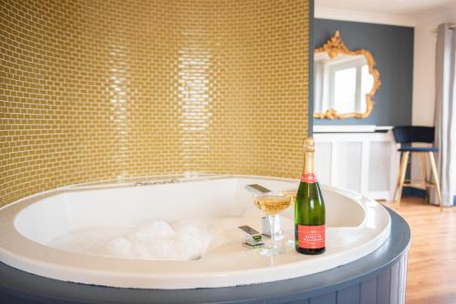 a bath tub with a bottle of wine and a glass at The Paddocks Cottage in Westward Ho