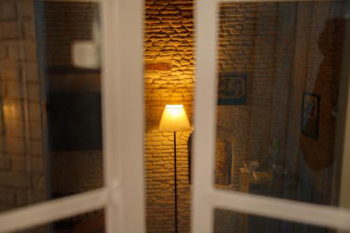 a lamp in a room next to a brick wall at Houch El Houdou in Tozeur