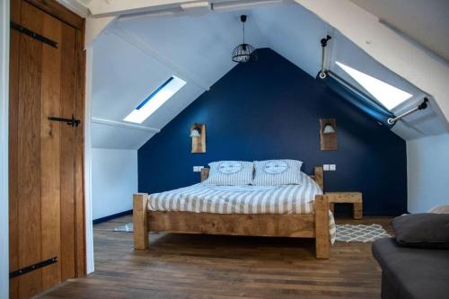 une chambre avec un lit avec un mur bleu dans l'établissement Maison au bord de la rivière, à Saint-James