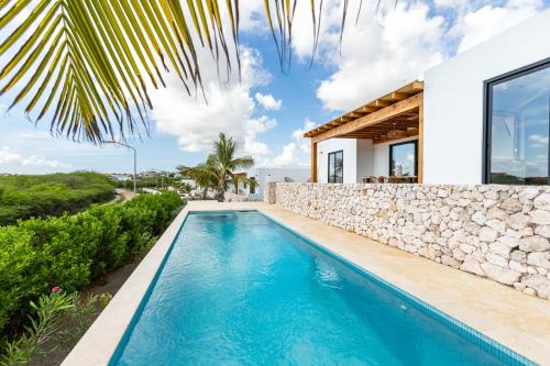 a villa with a swimming pool and a stone wall at LXRY Villas in Jan Thiel