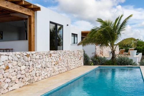a villa with a swimming pool and a stone wall at LXRY Villas in Jan Thiel