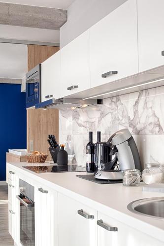 a kitchen with white cabinets and a sink at MLOFT Apartments München in Munich