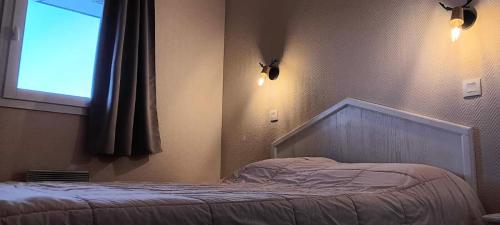 Ce lit se trouve dans une chambre dotée d'une fenêtre et de lumières. dans l'établissement Résidence Le Thabor - maeva Home - Appartement 2 Pièces 5 Personnes - Sélection MAE-9794, à Le Désert