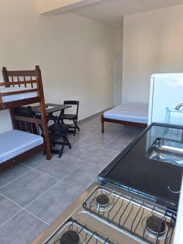 a kitchen with a stove and a table and a refrigerator at Casa da Maria Ubatuba in Ubatuba