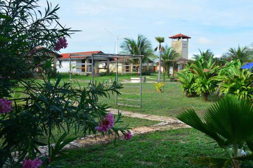 a park with a building and trees and flowers at Pousada Oceania in Taíba