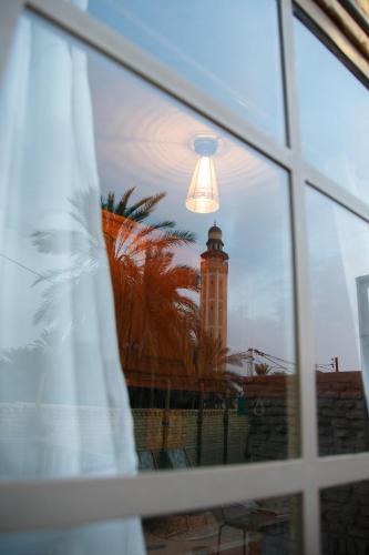 a reflection of a clock tower in a window at Houch El Houdou in Tozeur